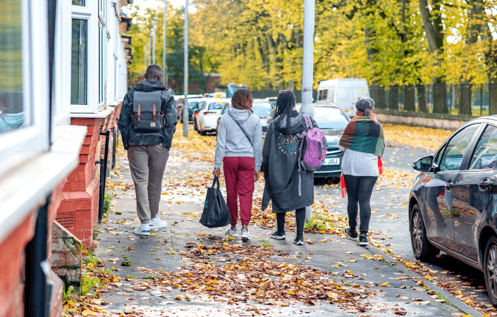 4 people walking down a residential street in the leaves